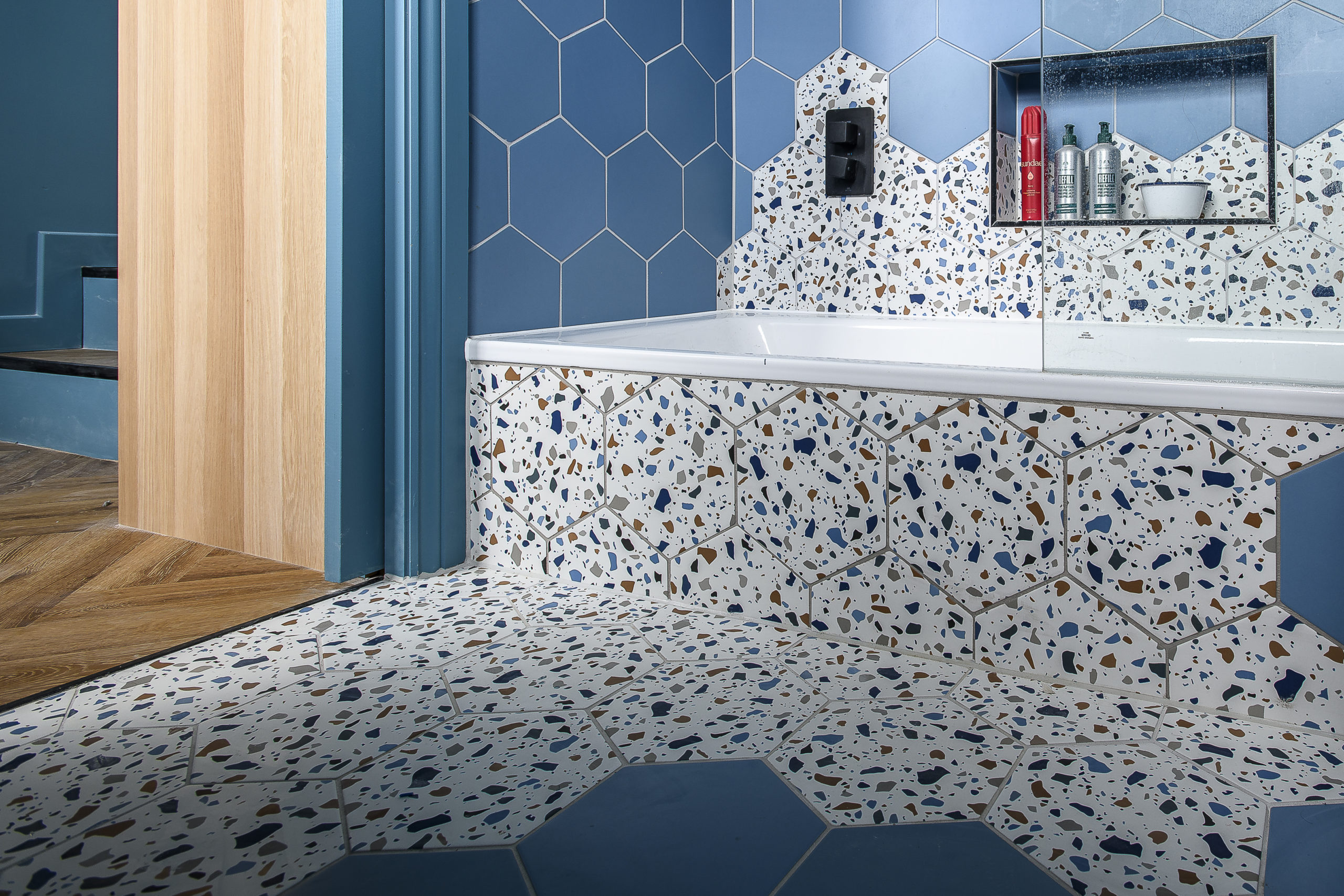 Brighton Architects Modern bathroom interior featuring terrazzo tiles, hexagonal wall tiles, built-in bath and bespoke joinery detailing.